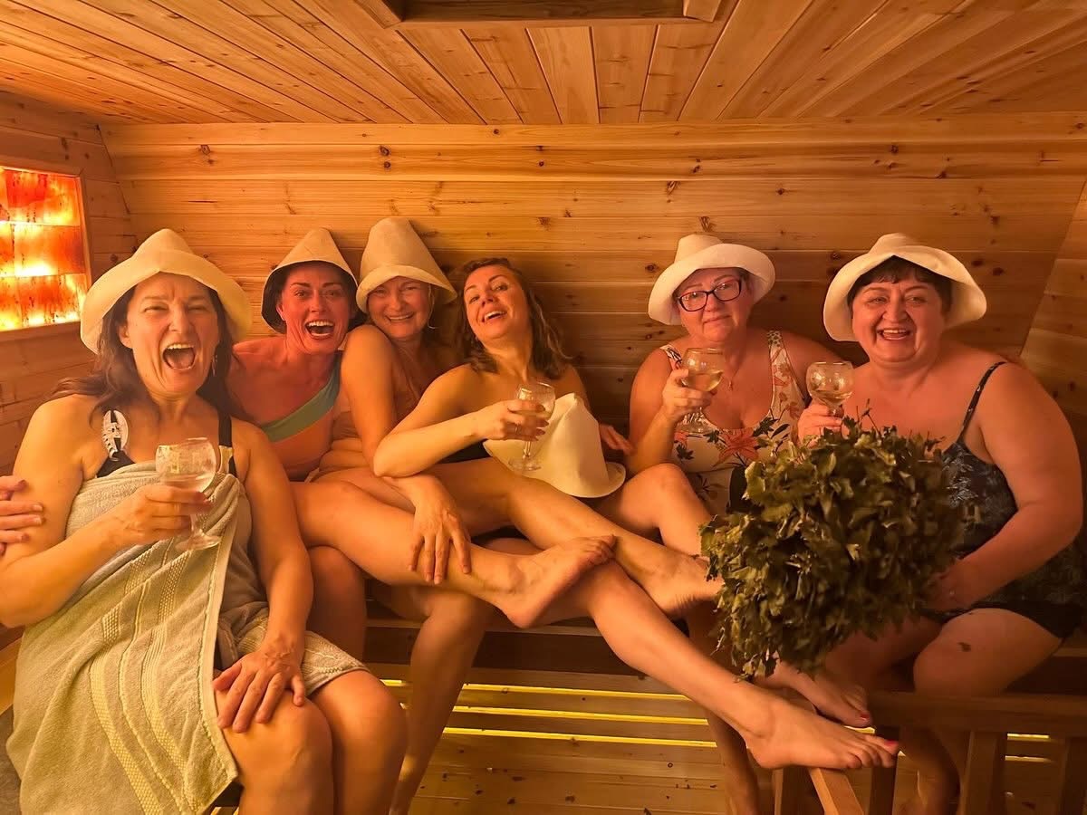 A group of friends laughing together on the benches inside the wood-fired sauna