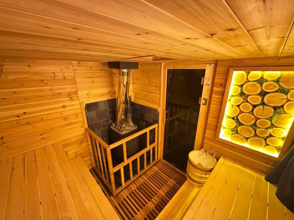 Interior of the cedar sauna with the wood stove and backlit wood-round window