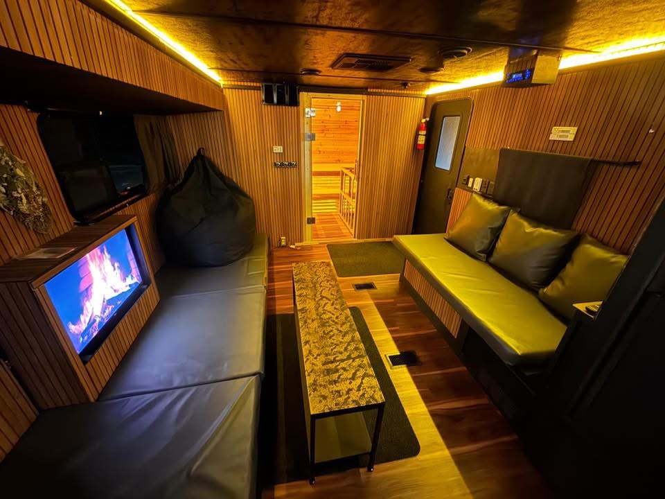 The warm lit lounge inside the trailer with leather benches and a fire screen